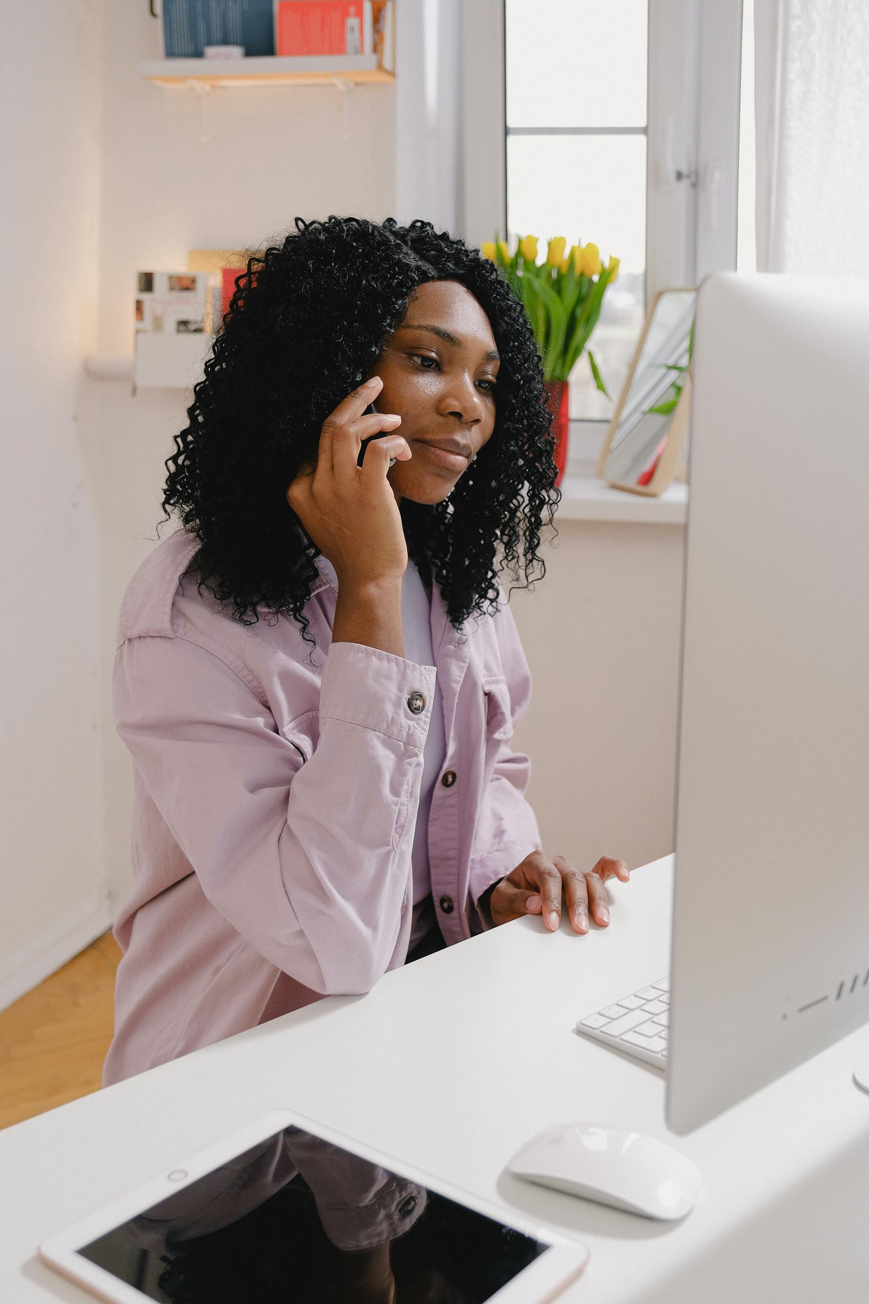 Glad African American female with curly hair having conversation on mobile phone at home